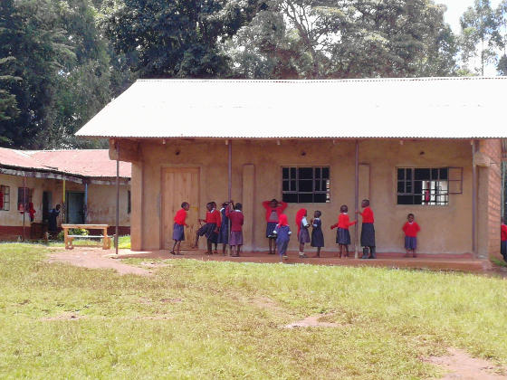 A small building with a corrugated roof and African children outside it